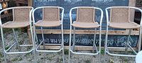 Front view of all four matching rattan bar stools lined up