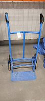 Front view of blue stair-climbing dolly showing frame, handles, toe plate