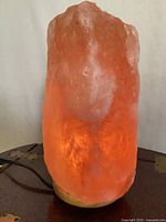 Rose quartz lamp illuminated on wooden base with cord