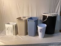 Line-up of all five wastebaskets and laundry basket