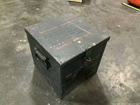 Three-quarter view of closed box showing side handle and stencil text