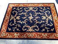 Full view of navy and rust floral wool rug