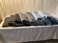 Seven folded moving blankets in assorted colors on table