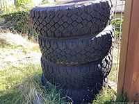Stack of four studded truck tires outdoors