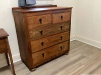 Front view of solid wood dresser showing five drawers and bun feet