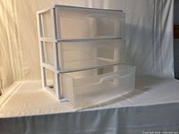 three-drawer translucent plastic dresser, one drawer open, side angle