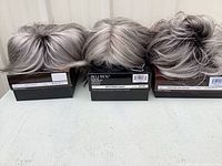 Three wigs on boxes front view