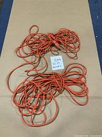 Two coils of orange extension cords with length note