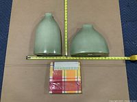 Two green vases measured against tape and packaged tablecloth