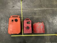 Front view of three fuel tanks side by side with measuring tape for scale