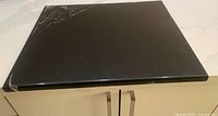 Top view of entire black acrylic chopping board on countertop, protective film visible