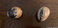 Both carved stone eggs on wood surface
