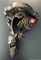 Front angled view showing carved shape, floral paint and red knob
