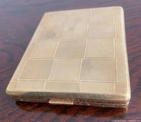 Closed cigarette case top showing checkerboard engine-turned pattern