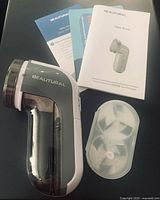 Beautural fabric shaver with manuals, clear head cover and spare blade visible