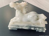 left side view of carved stone horse showing veining, speckles and base