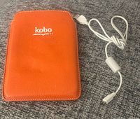 Front of Kobo eReader in orange Roots case with USB cable
