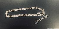 Full view of sterling silver bracelet laid flat showing extender and heart tag