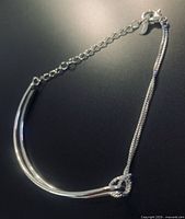 Full view showing twin curved bars, knot, chain and clasp
