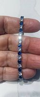 Close-up of bracelet held in hand showing alternating blue and clear stones