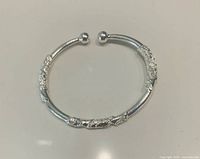 Top view of sterling silver open bangle showing floral carving and ball ends
