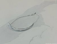 Entire bracelet laid flat showing double curved bar and chains