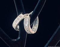 pair of sterling silver hoop earrings hanging on stand