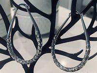 Front view showing teardrop hoop shape and faceted texture