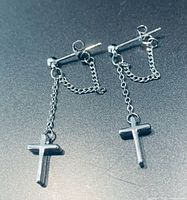 Front view of both earrings on flat surface showing chain drop and cross charms