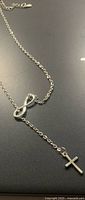 Full view of sterling silver necklace with infinity symbol and cross drop
