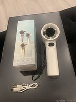 Fan with retail box and charging cable displayed on table