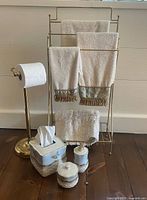 Overall view showing towel rack, toilet paper holder, towels, bath mat and ceramic accessories