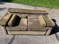 Front view of brown upholstered loveseat with two bolster pillows on pavement