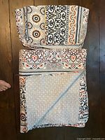 Folded queen bedspread with matching sham on top showing front and reverse patterns