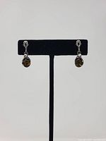 Front view of sterling silver Baltic amber drop earrings on stand