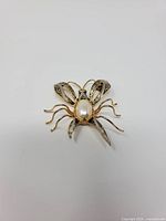 front view of insect brooch showing faux pearl body and wing details