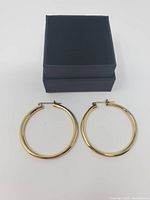 Hoop earrings laid flat beside closed black gift box