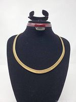 Full view of gold-tone collar necklace on display bust