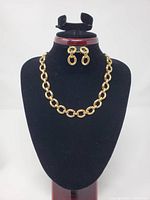 Necklace displayed on stand with earrings above