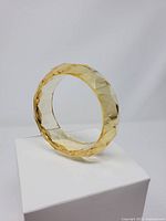 Side view of translucent faceted pale yellow lucite bangle