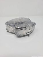 Front angled view showing scalloped lid curvature and two foliate feet