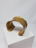 Angled view of brass cuff showing open design and overall shape