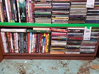 Full view of two shelves showing horizontal stacks of music CDs and vertical row of DVDs/CDs