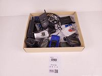 Top view of entire lot inside box showing cellphones, cameras, pagers, cables