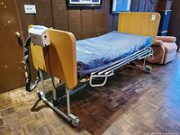 Full view of adjustable bed with mattress, rail, wheels, head and foot boards