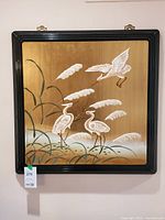 Front view showing relief birds, reeds, gold background, black frame