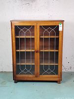 Front view of wood cabinet showing glass doors and interior shelves