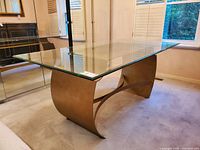 Angled view showing glass top and sculptural metal base