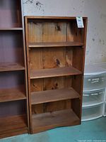 Front view of solid wood bookcase next to another unit, showing overall appearance