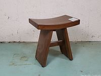 Front view of teak stool showing curved seat and legs
